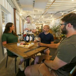 Group sitting at a table being presented a Linganore Winecellars bottle of wine during a tasting